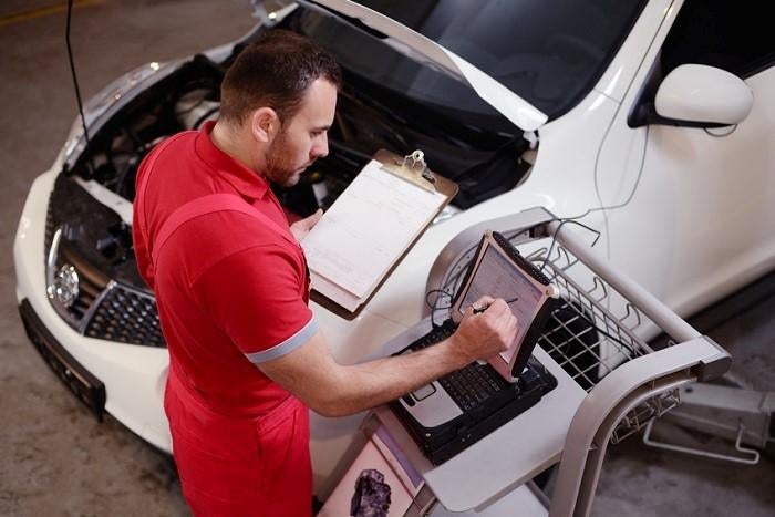 Technician performs car service on a white vehicle at Rick Weaver Buick GMC.