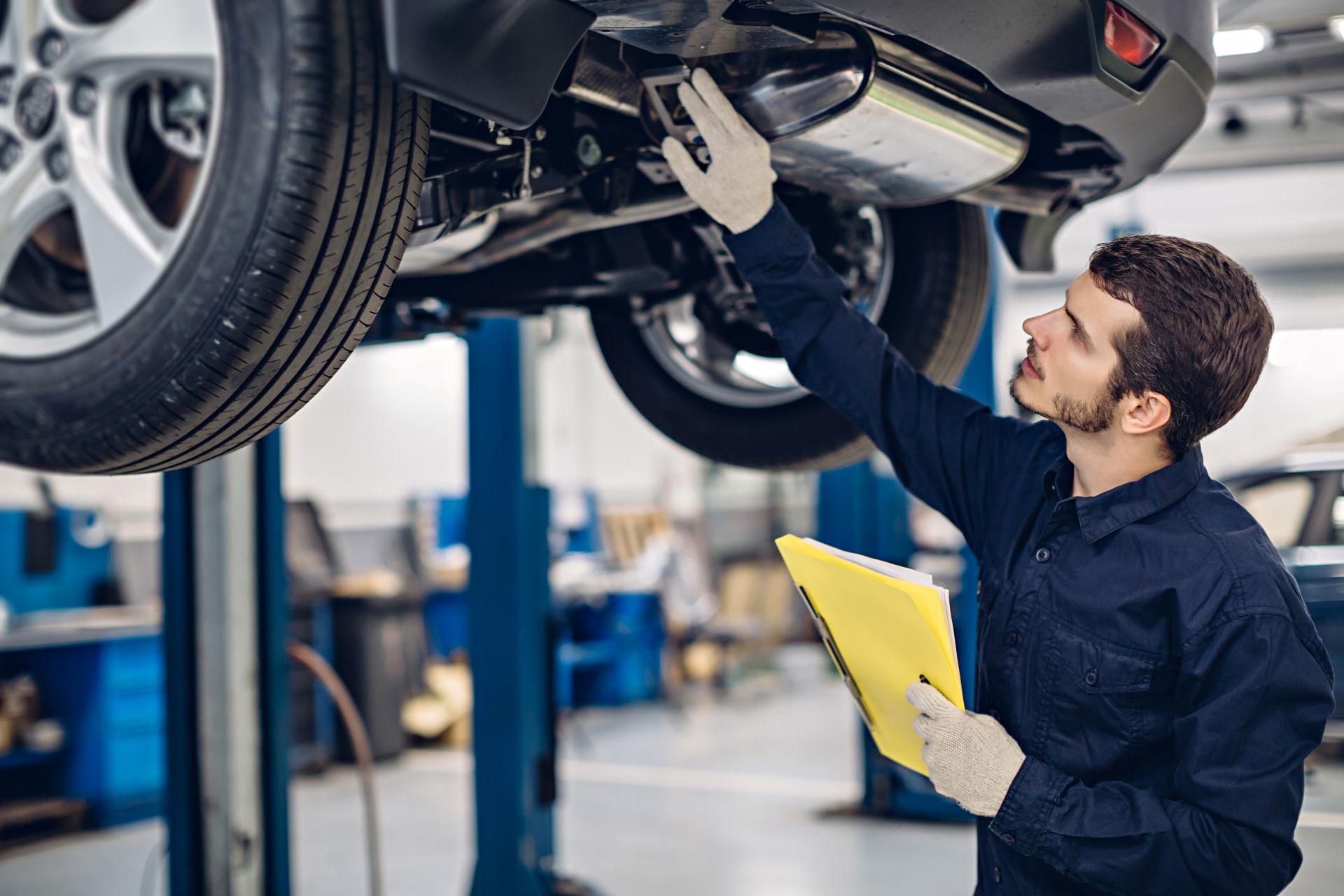 Service technician inspecting underside of car