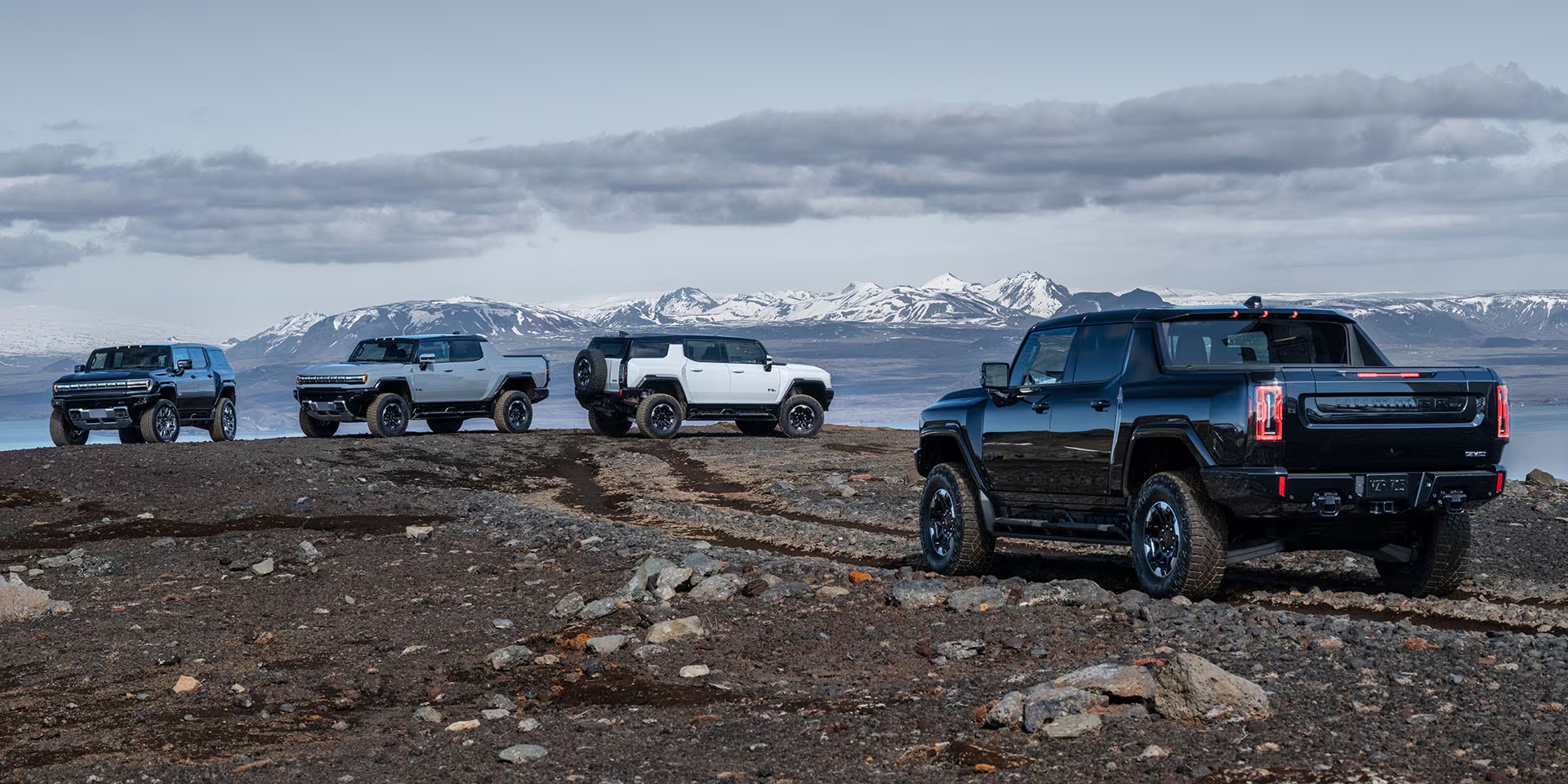 GMC HUMMER EV Pickup driving towards several GMC HUMMER EV SUVs on a mountain trail